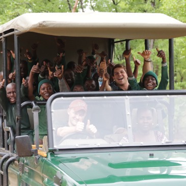 Man and children in a game drive vehicle.